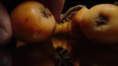 Erkek El, Kara Masa 'da Loquats' ı seçerken kamera ileri kayıyor. Siyah Arkaplanda Macro Dolly.