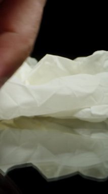 Dikey video. Siyah Masa 'ya Uzanan Elle Tıbbi Lastik Eldivenler' in yakın çekimi.