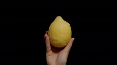 Kara Arkaplanda Alttan Bir Büyük Limon Bir Kadının Elinde Görünüyor.
