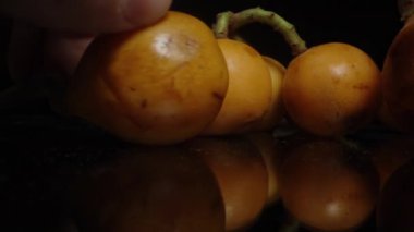Kara Masa 'daki Loquats, Dolly Kaypak Aşırı Yakın plan. Erkek El Meyveleri Toplar.