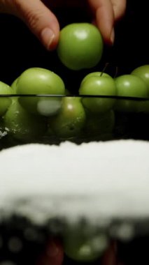 Dikey video. Kadının Elleri Yeşil Kiraz Eriğini Tuz Yığını 'na batırıyor, Siyah Arkaplan' a yakın plan.