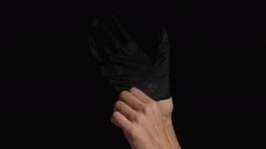 Bir kadının eli siyah bir lateks eldiven takar. Kara Arkaplanda İzole Edilmiş.