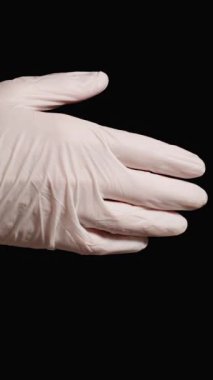 Dikey video. Siyah ve beyaz eldivenli doktorlar arasında tokalaşma. Selamlama ya da Minnettarlık Hareketi, tecrit.