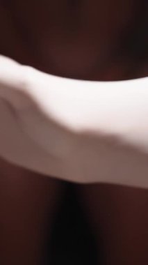 Dikey video. Kadın Doktor 'un Elleri Çıplak Adam' ın Önünde Beyaz Lateks Eldivenleri Giyiyor ve Kendini Elleriyle Örtüyor. İnceleme Konsepti.