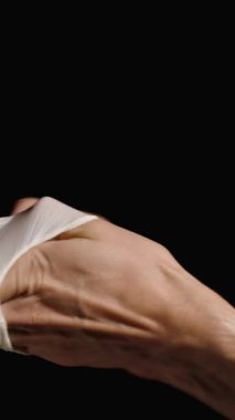 Dikey video. Beyaz lateks eldivenleri takan kadın eli, doktor muayeneye hazırlanıyor. Kara Arkaplanda İzole Edilmiş.