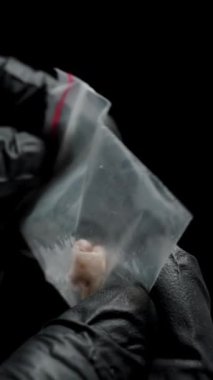 Dikey video. Siyah Eldivenli Eller Küçük Kanıt Çantasında İnsan Dişi İnceleme.