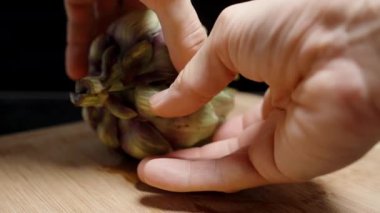 Taze Bir Enginarın İki Yarısı Erkek Ellerinde Bud 'ın İçini Gösteriyor.