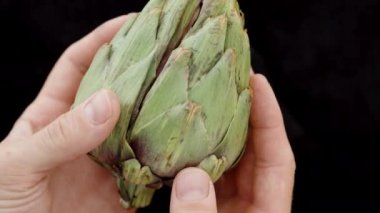 Erkek Eller taze bir enginarı ikiye bölerek, iç çekimin yakın çekimini gösterir.
