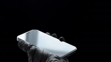 Bir Akıllı Telefon Perdesini Turuncu bir bezle silmek, Siyah Eldivenli Bir İnsan. Tamir Dükkanı Konsepti.