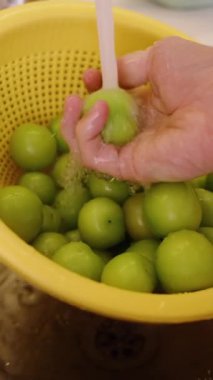 Dikey video. Metal bir lavabonun altında, Erkek Elleri Yeşil Kiraz Eriklerini Yıkıyor. Yavaş Hareket.