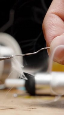 Dikey video. Demir Eritme Kalay Kablosu, Duman Parçacıkları Spreyi. Arka planda çeşitli araçlarla Elektronik Tamir için Atölye Tablosu.