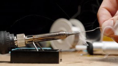 Demir Eritme Kalay Kablosu, Duman Parçacıkları Spreyi. Arka planda çeşitli araçlarla Elektronik Tamir için Atölye Tablosu.