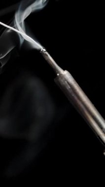 Dikey video. Siyah Arkaplanda Demir Kaplama Sıcak Uç 'ta Eriyen Spermden Duman Ediyor.