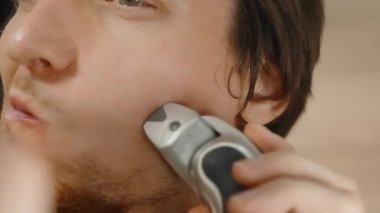 Yanak Arkası ve Önü Elektrikli Ustura Kullanan Genç Adam, Yavaş Hareket. Banyodaki Ayna 'da Sabah Rutini.