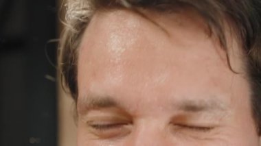 Genç adam aynada kendine bakıyor ve yüzünü suyla yıkıyor, yavaş hareket ediyor..