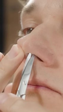 Dikey video. Aynanın Önündeki Genç Adam Burun Ucunu İçerideki Tüylere Kaldırıyor, Yavaş Hareket.