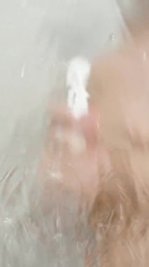 Dikey video. Duşun Arkasındaki Çıplak Adam Cam Kapı Sprey Su, Yavaş Hareket.