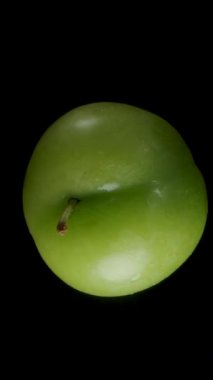 Dikey video. Yeşil erik yavaşça bir kadının avucuna düşer, Macro Zoom, izole edilmiş..