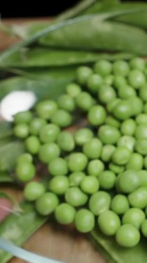 Dikey video. Kameranın önünde bezelye tabağını sallıyor, ağır çekimde..