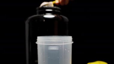 Protein tozunu bir bardak suya boşaltıyorum. Yavaş Çekim, Siyah Arkaplanda Titreşim, Çalışma Öncesi Hazırlık.
