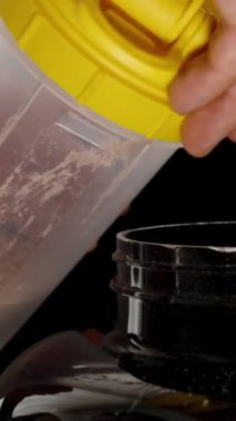 Dikey video. İçinde protein tozu olan bir Shaker 'ı kapatan adam. Siyah Arkaplanda.