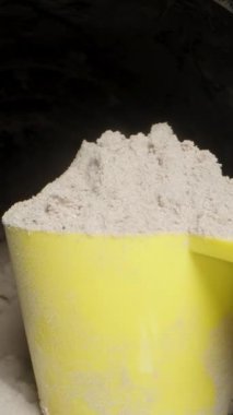 Dikey video. POV, kavanozdan Protein tozu dolu sarı bir kaşık çıkarıldı. Sağlıklı Spor Beslenme.