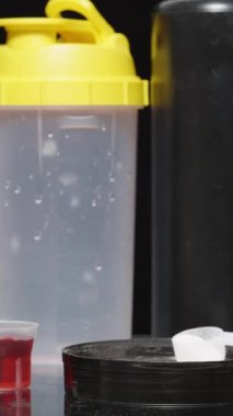 Dikey video. Spor malzemelerinin çeşitliliğini gösteren bir adam, bir kaşık protein tozu seçer..