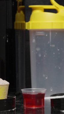 Dikey video. Spor malzemeleri ve vitaminler masaya konur, bir adam alınmaması gerekenleri gösterir ve küçük bir kaşık beyaz toz seçer. Tüm İlaveler Sağlıklı Değil.