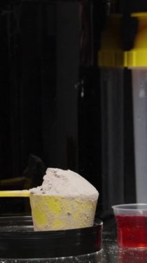 Dikey video. Bir adam küçük bir kaşığı beyaz pudrayla temizler ve yanına koyar. Spor Eklentilerinin Farklılığı Konsepti.