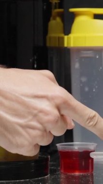 Dikey video. Bir erkek, beyaz kreatin tozuyla bir kaşığı atletlere doğrultur ve baş parmağıyla onaylar. Spor için Vitamin Seçimi.