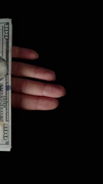 Dikey video. Bir yığın dolar teker teker elden uçup gidiyor. Harcanmış para, her zaman parasız kalma ve boşa harcama kavramı..