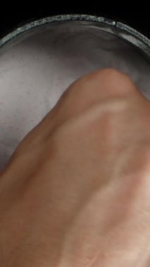 Dikey video. Bir adam beyaz tozu bir ölçü kaşığının içine koyar, kameraya getirir ve kabın içine geri döker. Zararlı Ek Bilgileri Reddetme Konsepti.