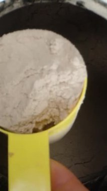 Dikey video. Büyük bir kutu çikolatalı Protein tozu, bir kaşıkla bir porsiyonu kepçelemek ama hepsini geri dökmek..
