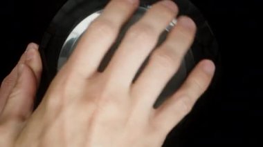 Protein tozu kabının siyah kaplamasını sökerek kamera, spor malzemesini ölçüm kaşığıyla filme alarak kutuya girer..