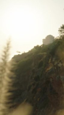 Dikey video. Uçsuz bucaksız deniz sonsuzluğun bir resmi ve tabiatın majestesi rüzgarın savurduğu kuru otların arasından geçen yüksek bir dağdan..