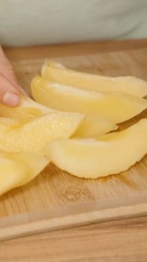 Dikey video. Dikey video. Pepino Meyve Kesme Tahtasında Dilimler, Derilerini Yüzen Kadın.