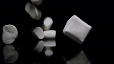 Beyaz şekerlemeler Siyah Yansıtıcı Masa 'ya Düşüyor, Yavaş Hareket, Yakın Çekim.