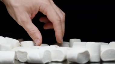 Masadan bir lokum alıp Siyah Arkaplan 'a karşı Yumuşak Şeker Dokusunu Göstermek.