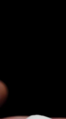 Dikey video. Beyaz Şekerli Şekerin Yakın Çekimi Bir Erkek El Altından Siyah Bir Arkaplanda Ortaya Çıktı.