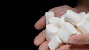 Adam yavaşça ellerinden bir sürü beyaz lokum döküyor. Sağlıksız Tatlı Yemek kavramı.