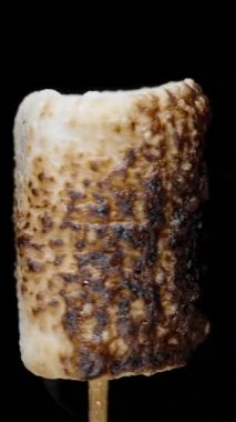 Dikey video. Çubukta Şekerleme Dönüyor ve Ateşde Kömürleşme, Siyah Arkaplanda Yakın Çekim.