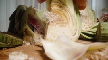 Parçalanmış enginar parçaları masaya saçılmış, birazını almış. Dolly Kaydırıcı, Yakın plan.