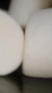 Dikey video. Siyah Yansıtıcı Masa 'da Marshmallow, Sayısız Şekerden Geçen Kamera. Dolly Kaydırıcı, Yakın plan.