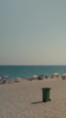 Dikey video. Güneş Şapkalı Kadın ve Şortlu Kadın Sahilden Uzaklara Tırmanıyor, Arka planda Deniz ve Dağlarla. Turizm ve Tatil Konsepti.