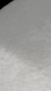 Dikey video. Yalnız Beyaz Marşmelov Dönüyor ve Siyah İzole Arkaplanda Düşüyor. Macro Zoom. Yavaş Hareket.