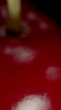 Dikey video. Yalnız Kiraz Dönüyor ve Düşüyor, Kara Arkaplanda Yalıtılmış, Dolly Zoom.