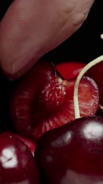 Dikey video. Kiraz Yarısı 'ndan El Sıkan Meyve Suyu, Siyah Arka plan' da Meyve Suyu, Macro. Yavaş Hareket.