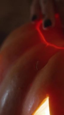 Dikey video. Parlak mum ışığı Fenerin içinde, Kadın oyulmuş Lid 'i kaldırır ve içine bakar..