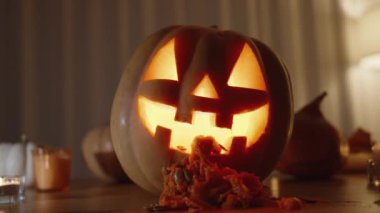 Cadılar Bayramı arka planı. Mum ışığından Jack-o '-Lantern ve Balkabağı Masada. Balkabağı ezmesi ve tohumlar ağızdan döküldü..