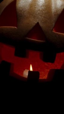 Dikey video. Mum, Jack-O 'Lantern' ın içinde söner, Kamera Balkabağına yaklaşır ve Uğursuz Gülümseme ile girer. Cadılar Bayramı sonu kavramı.